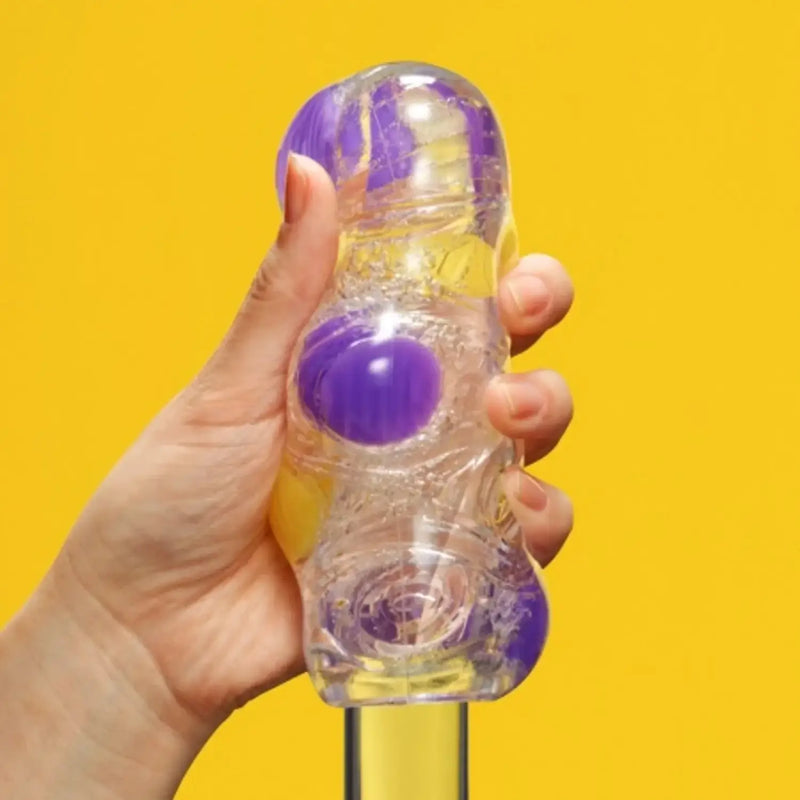 Hand holding TENGA BOBBLE MAGIC MARBLES with clear bottle and colorful magic marbles