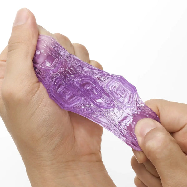 Translucent purple textured silicone sex toy being squeezed by hands from TENGA UNI VARIETY PACK