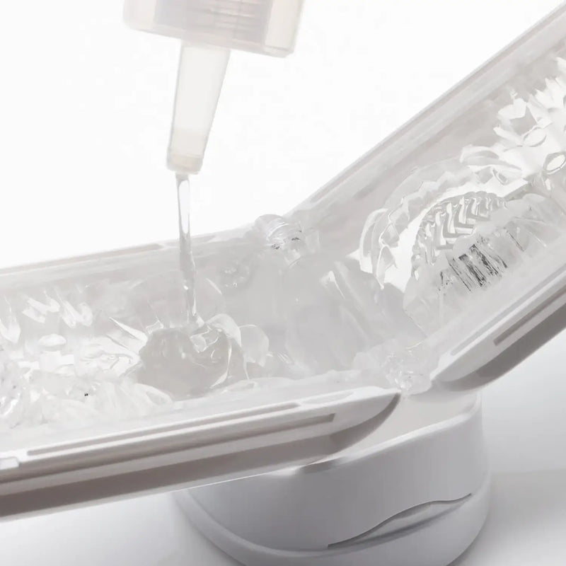 Clear liquid pouring into TENGA LOTION MILD ice cube tray, perfect for sex toy prep